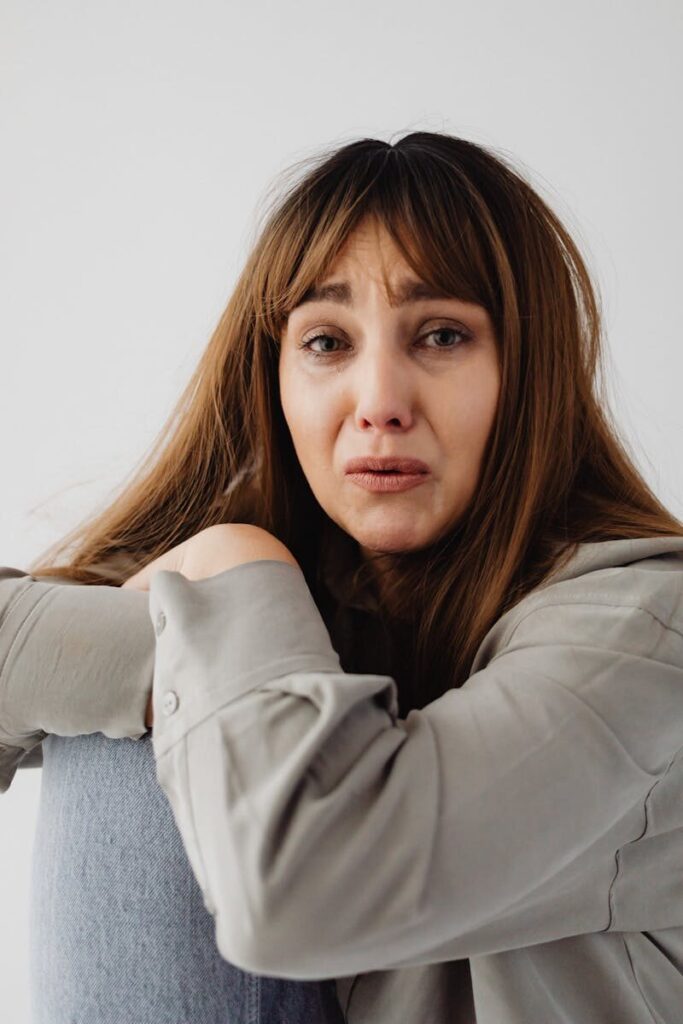 Close-up portrait of a woman expressing sadness and distress in a thoughtful pose.